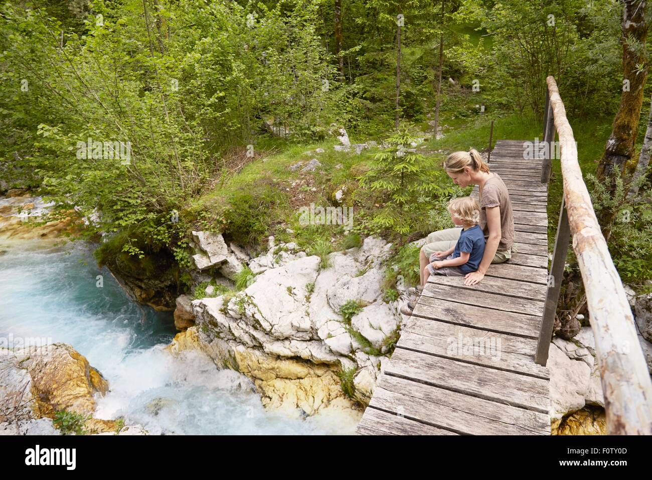 Donna matura con Figlio seduto sulla passerella in legno, Bovec, Soca, Slovenia Foto Stock