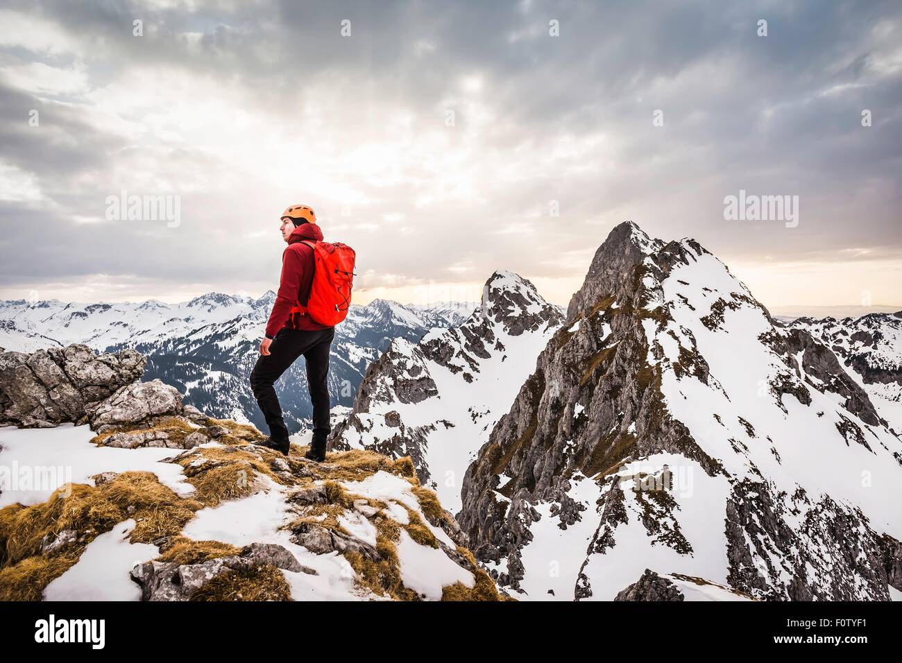 Vista posteriore di un escursionista guardando Snow capped montuosa, Kellenspitze, montagne di Tannheim, Tirolo, Austria Foto Stock