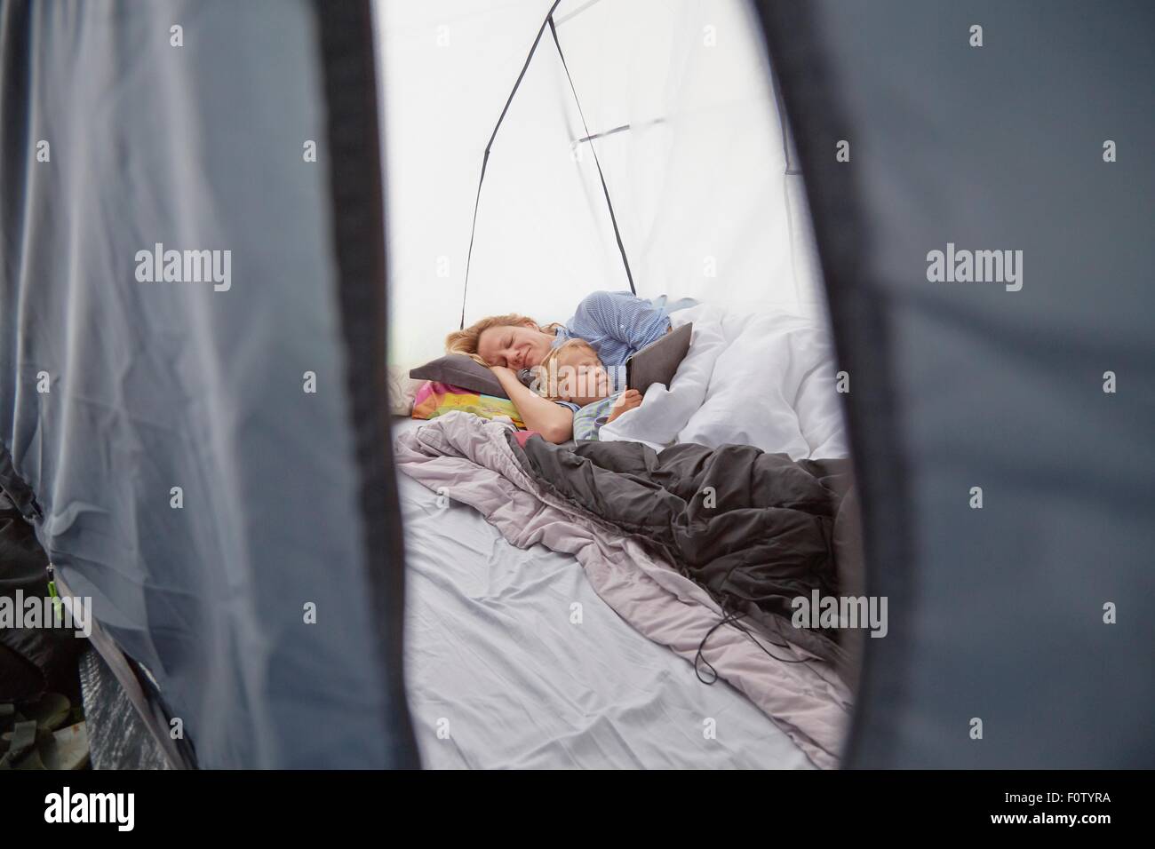 Madre giacente in tenda con toddler figlio utilizzando tavoletta digitale Foto Stock
