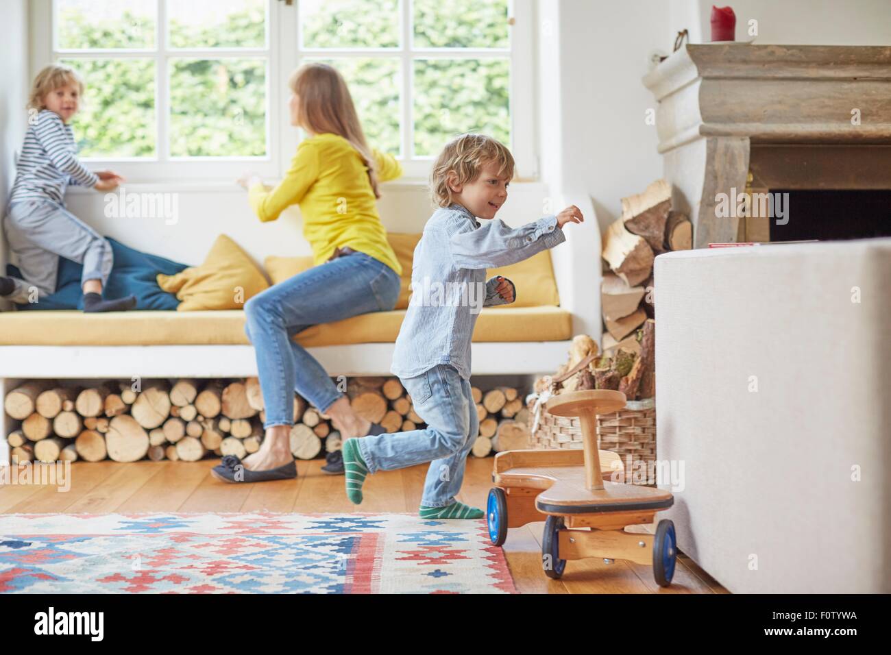 Madre guardando fuori della finestra mentre i suoi due figli giocare Foto Stock