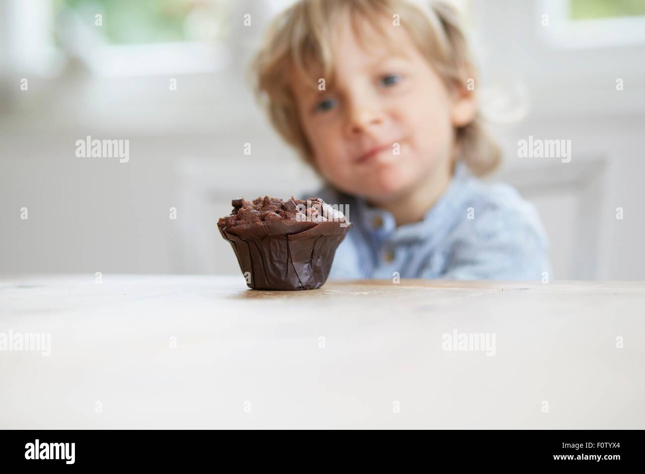 Ragazzo giovane fissando muffin al cioccolato Foto Stock