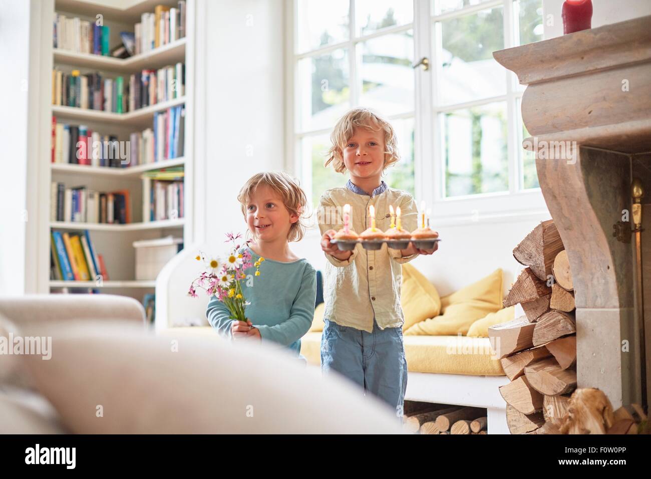 Due ragazzi tenendo i fiori e i tortini con cndles lit Foto Stock