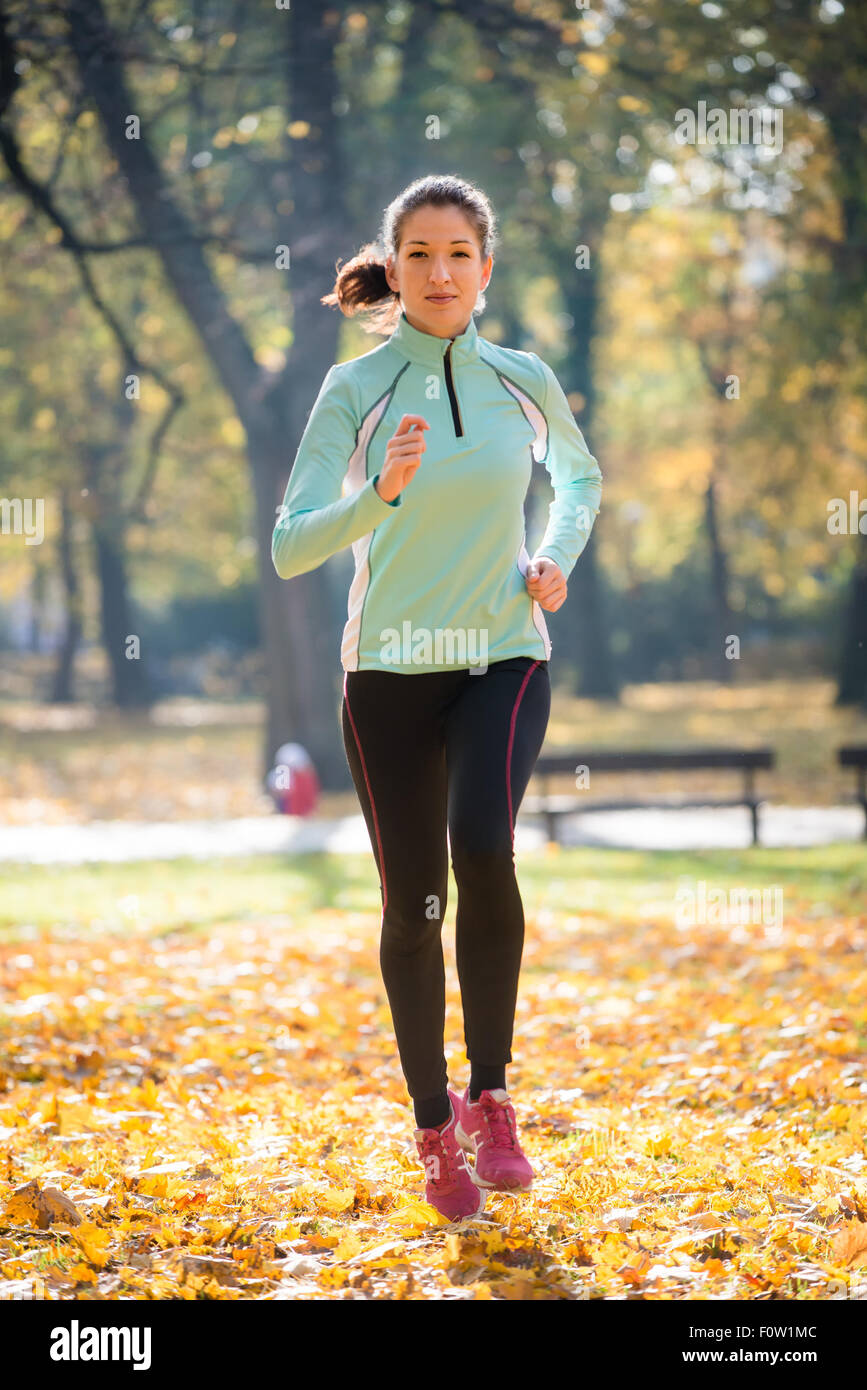 Giovane donna jogging e formazione in autunno la natura Foto Stock