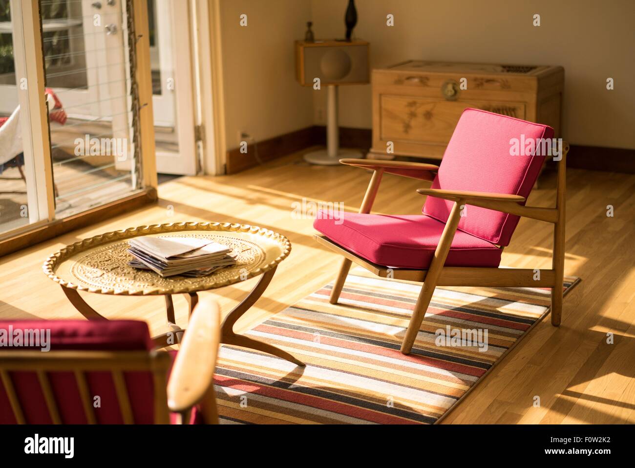 Soleggiato soggiorno con poltrone rosse e tavolo da caffè Foto Stock