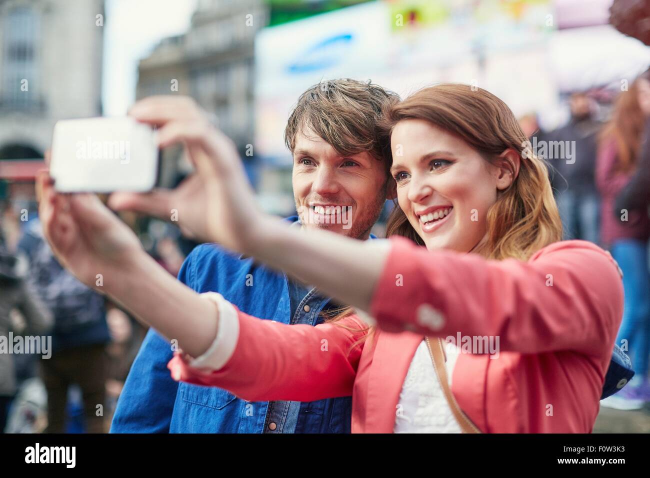 Turista giovane prendendo selfie smartphone a Piccadilly Circus, London, Regno Unito Foto Stock