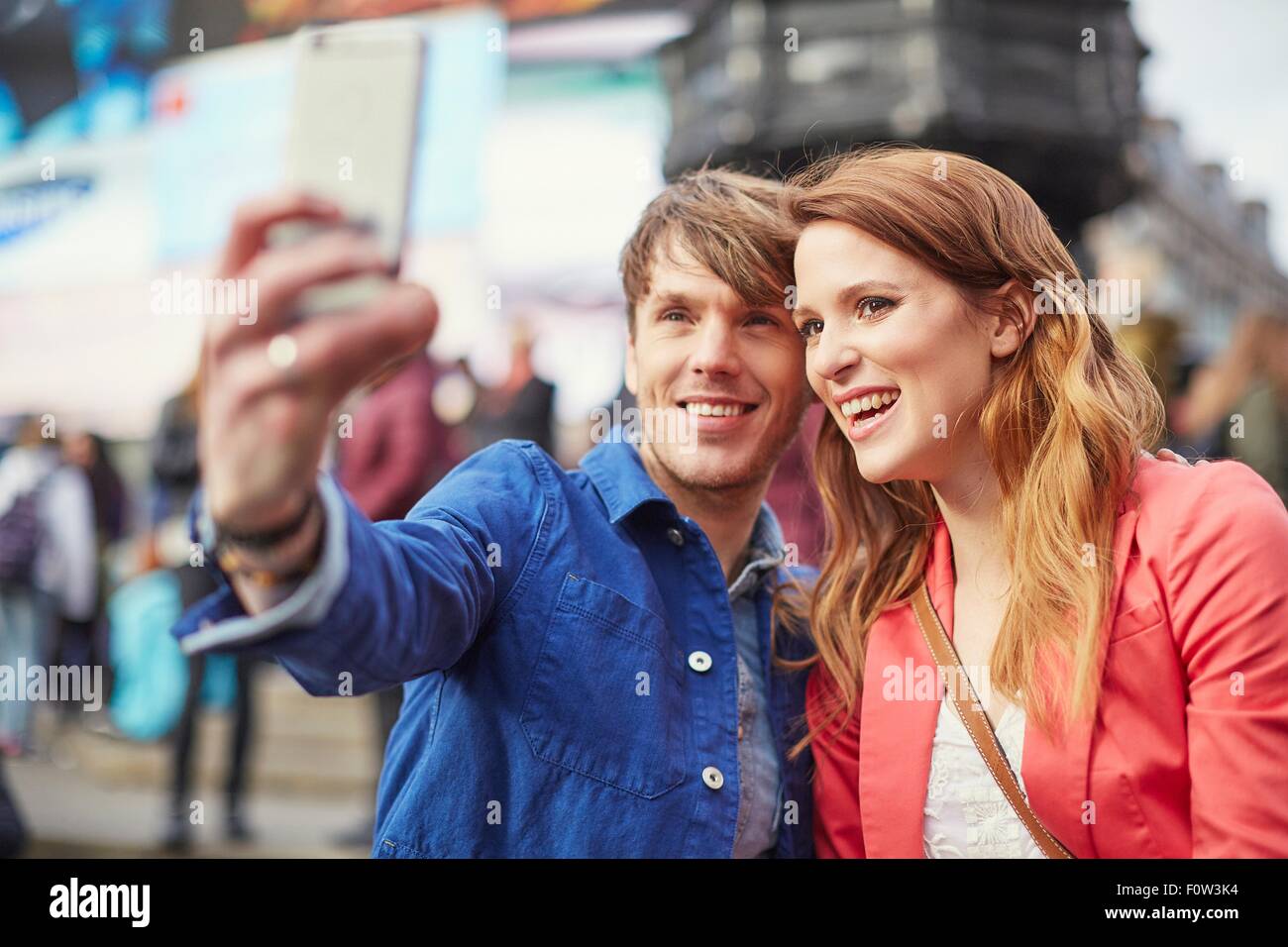 Turista giovane tenendo selfie sullo smartphone a Piccadilly Circus, London, Regno Unito Foto Stock