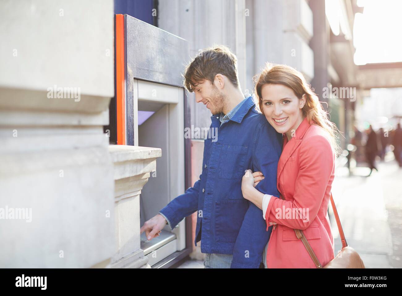 Giovane prelevare denaro da street bancomat, London, Regno Unito Foto Stock