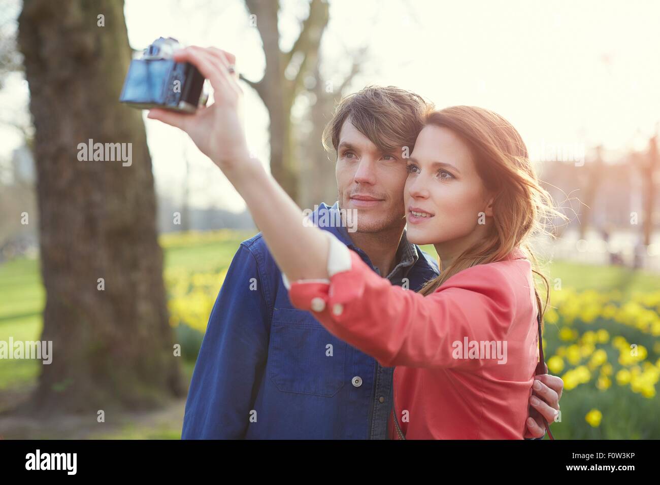 Giovane tenendo la fotocamera selfie in park, london, Regno Unito Foto Stock