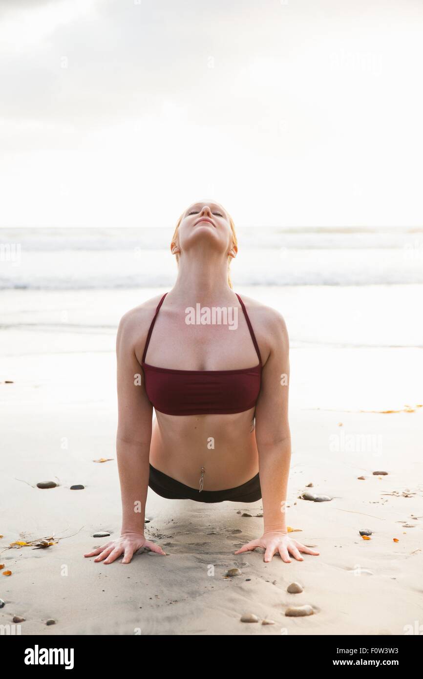 Metà donna adulta praticando yoga tavoloni pongono sulla spiaggia Foto Stock