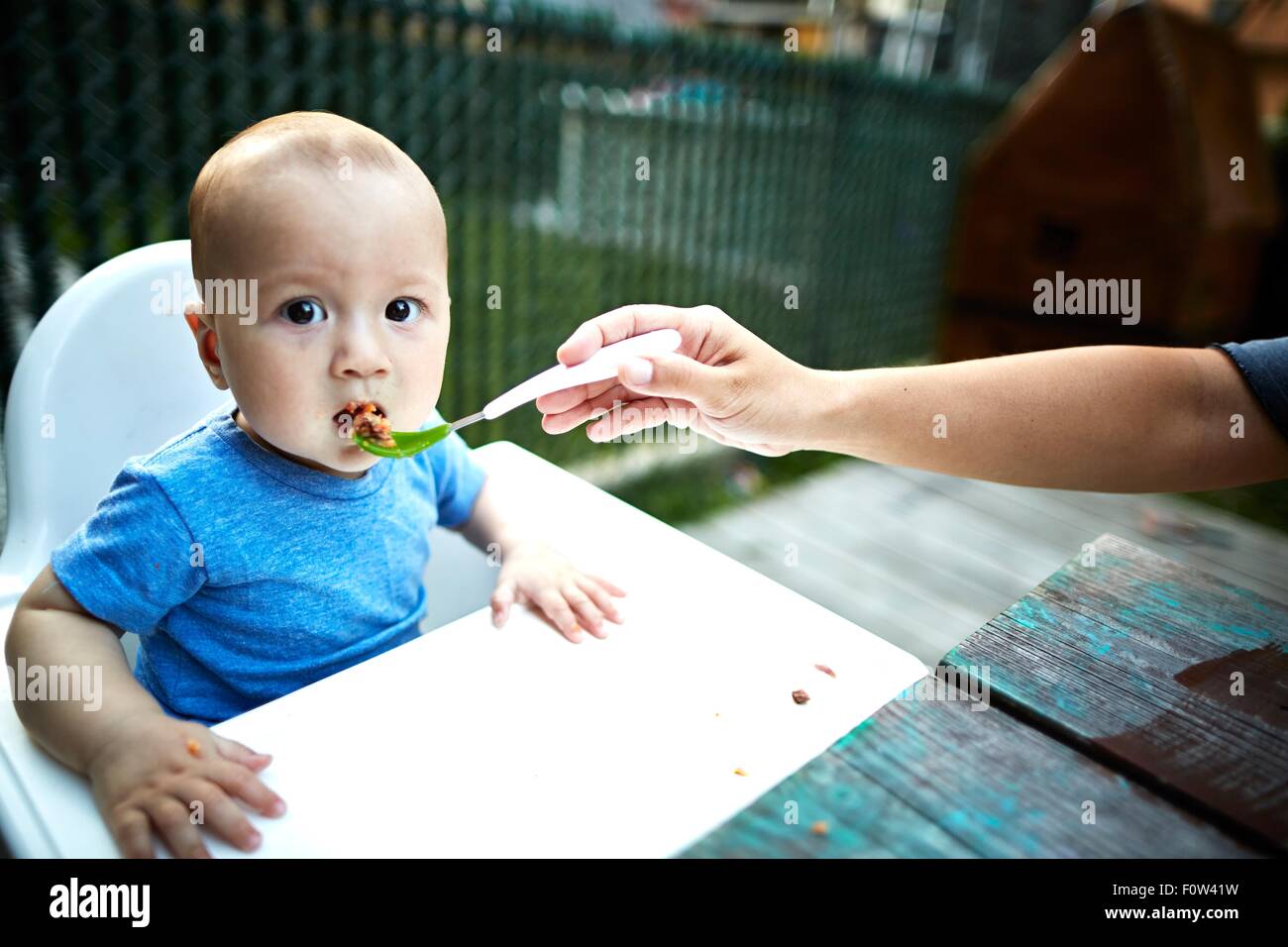 Padre figlio di alimentazione in alta sedia Foto Stock