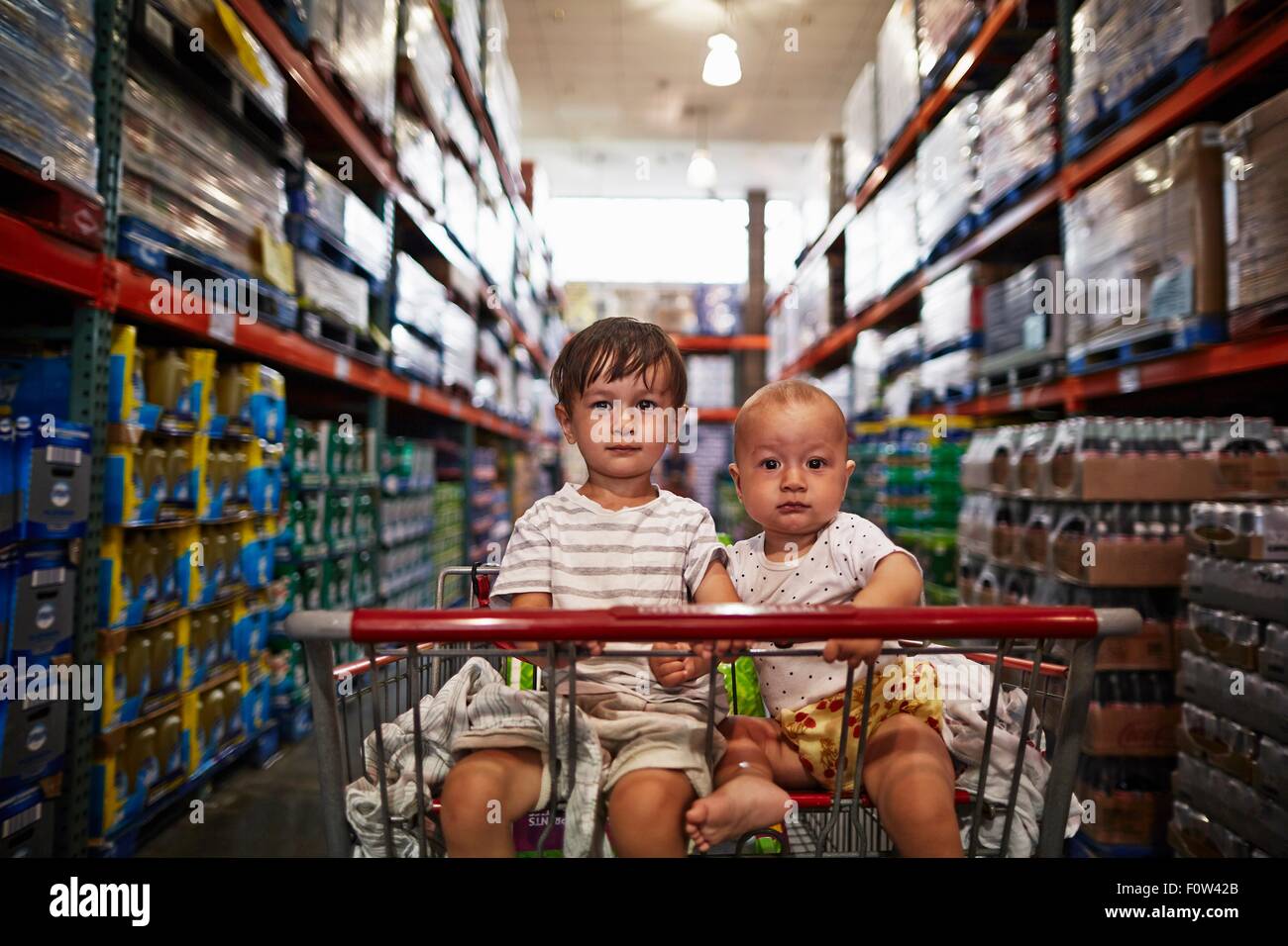 Fratelli seduto nel carrello della spesa Foto Stock