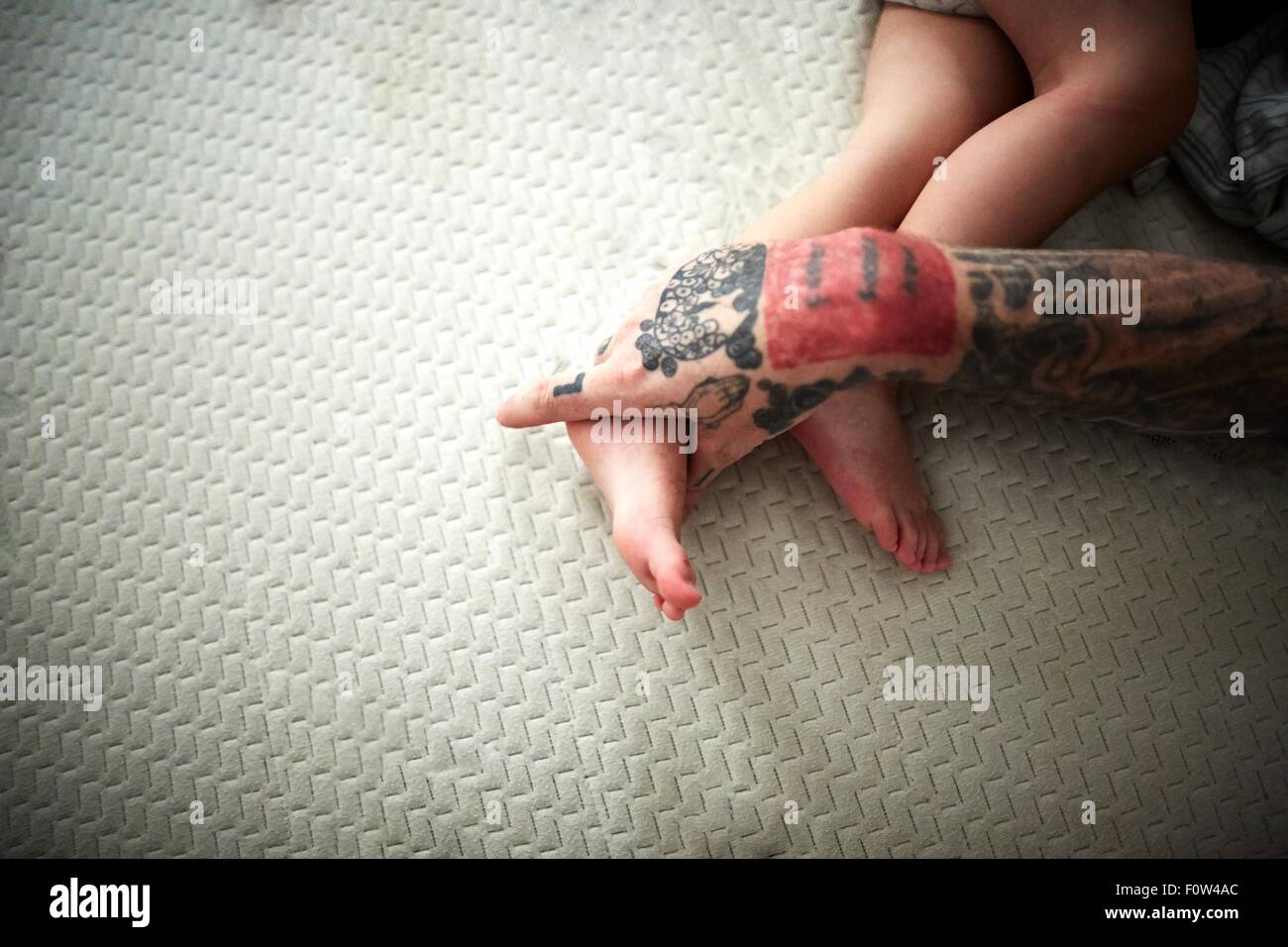 Tatuato mano appoggiata sul ragazzo per le gambe Foto Stock