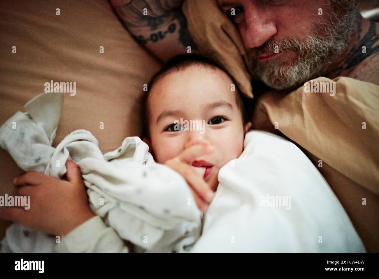 Padre e figlio sdraiato sul letto Foto Stock