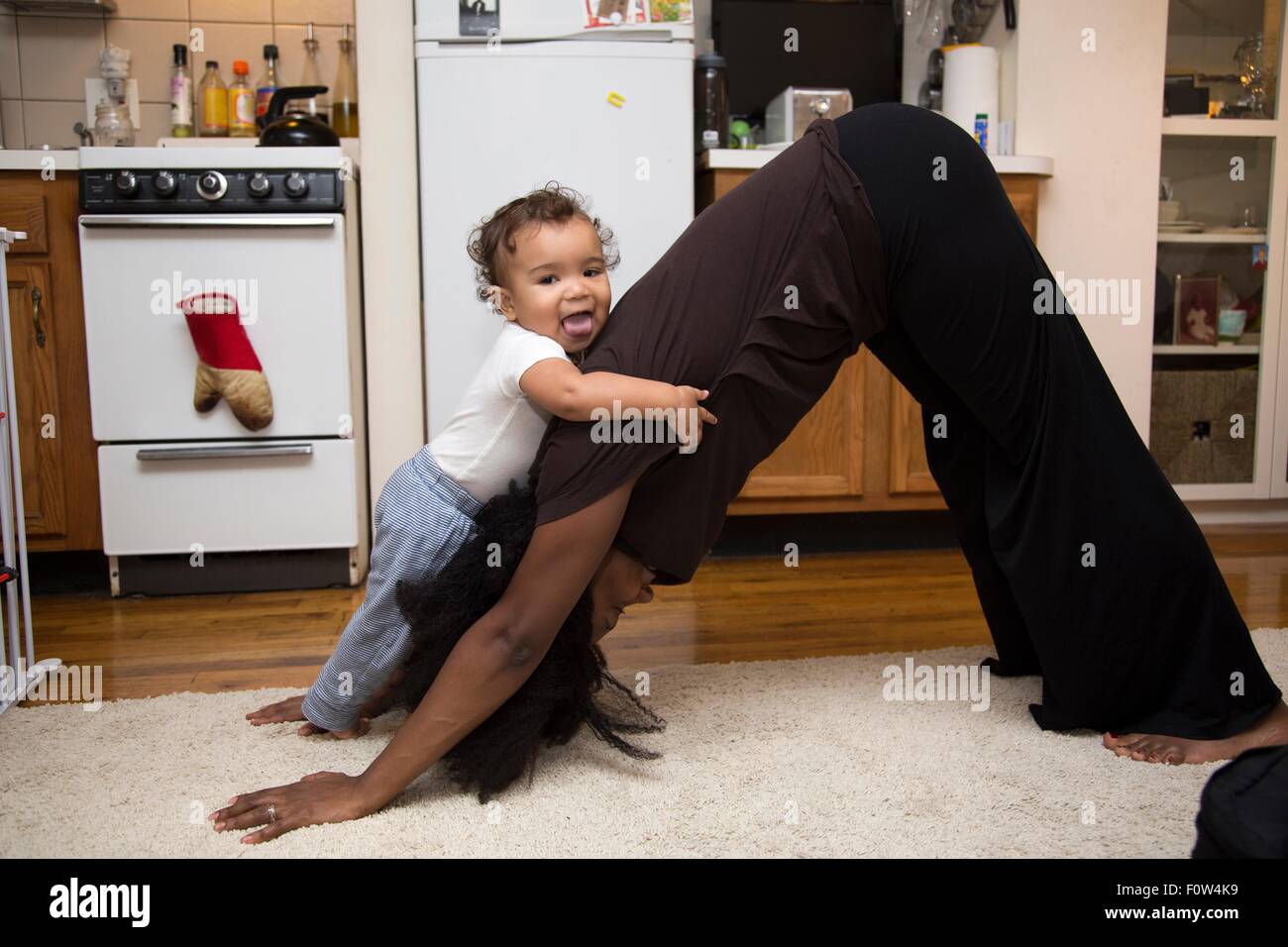 Metà donna adulta che esercitano sul tappeto con toddler figlia Foto Stock