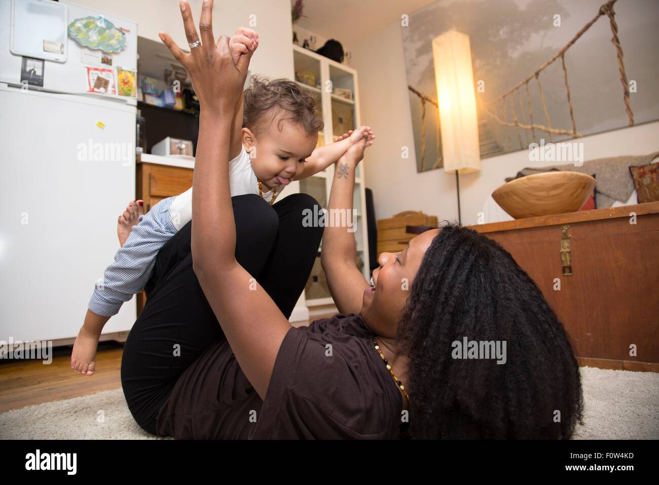 Metà donna adulta che giace sul tappeto a giocare con la figlia dei bimbi Foto Stock