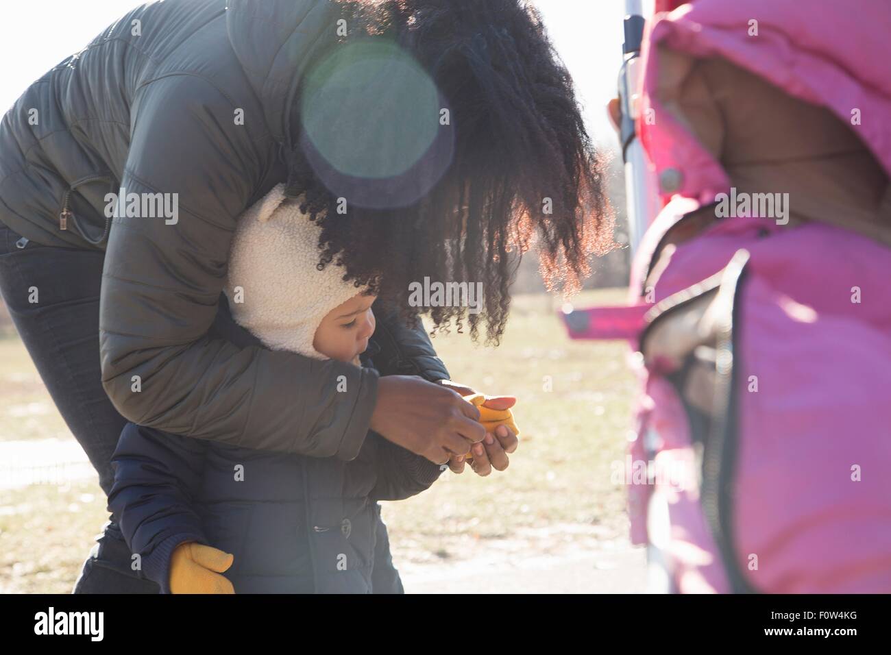 Metà donna adulta Mettere guanti in toddler figlia in posizione di parcheggio Foto Stock