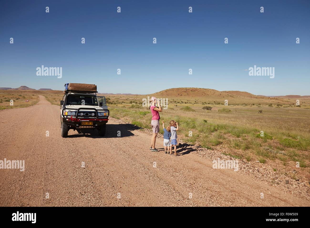 Off road veicolo parcheggiato mentre la madre e i bambini guardano a vista, Sesfontein, Kaokoland, Namibia Foto Stock