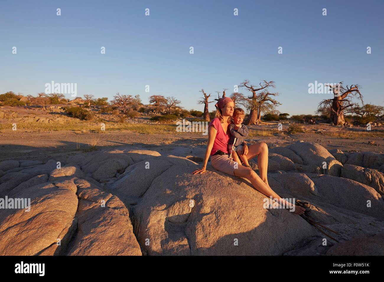 Madre e figlio seduti su roccia, guardando a vista, Gweta, makgadikgadi, Botswana Foto Stock