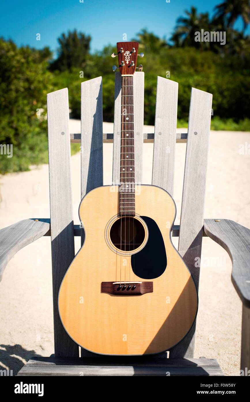 Chitarra acustica sulla spiaggia in legno sedia Foto Stock
