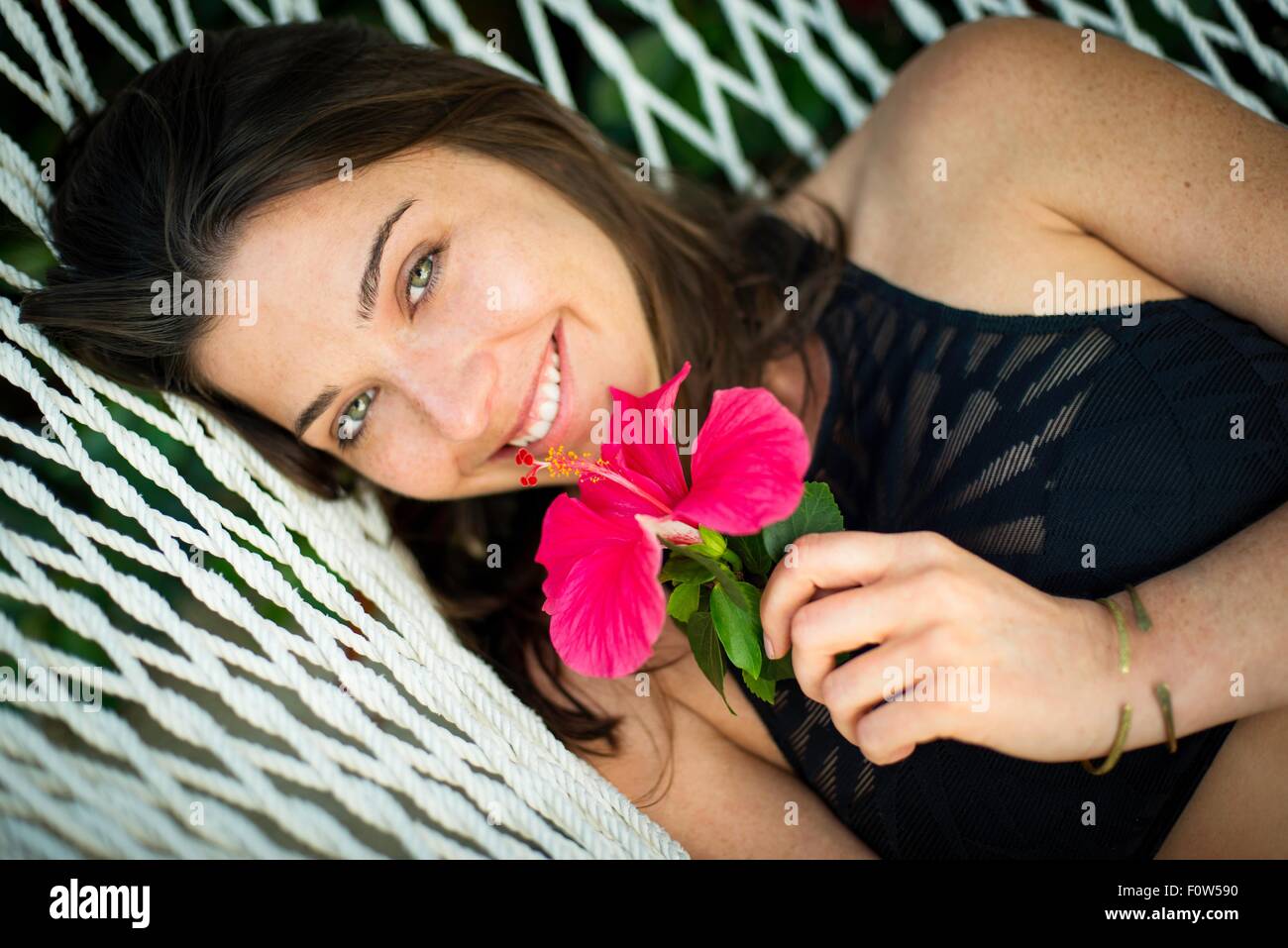 Ritratto di giovane donna sull'amaca con fiore rosa Foto Stock