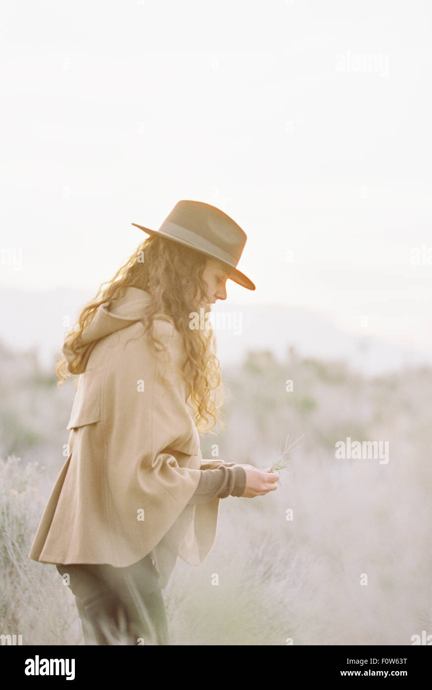 Una donna in una giacca calda e un cappello picking fiori selvatici. Foto Stock