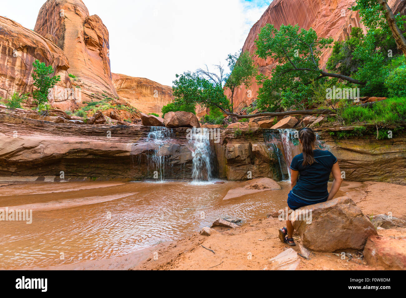 Ragazza escursionista guardando acqua piccola cascata Coyote Gulch Escalante Foto Stock