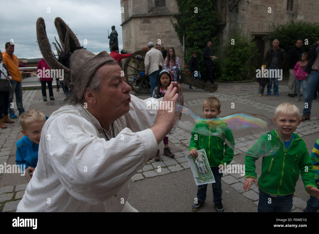 Un esecutore di strada gigante soffia bolle di sapone per intrattenere i bambini al Castello Hohenzollern, Baden-Wuerttemberg, Germania Foto Stock