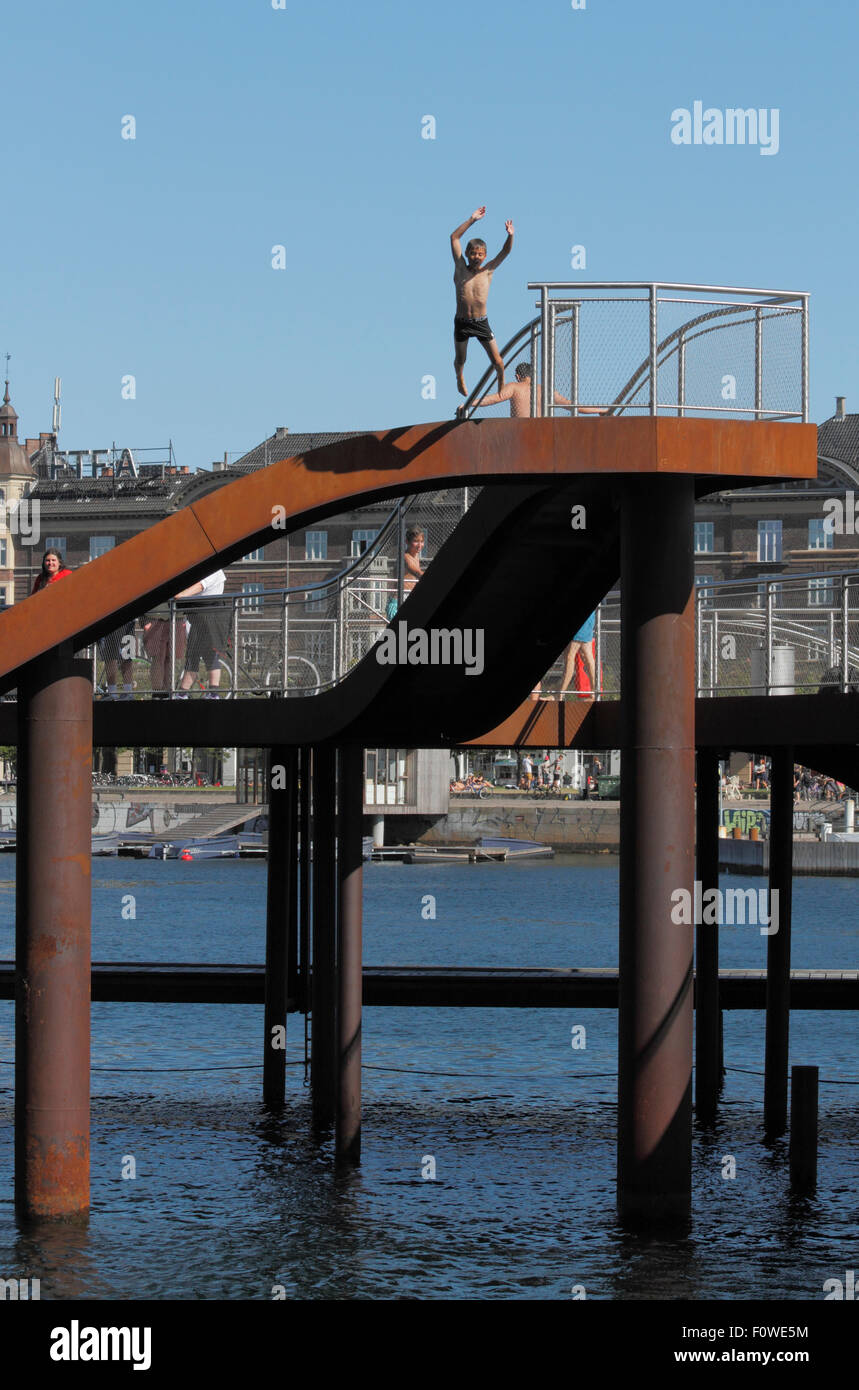 Ragazzo che salta dal Kalvebod Bølge, Kalvebod Waves o Wave, nel porto interno di Copenhagen. Spazio urbano, centro sociale, luogo per gli sport acquatici. Foto Stock