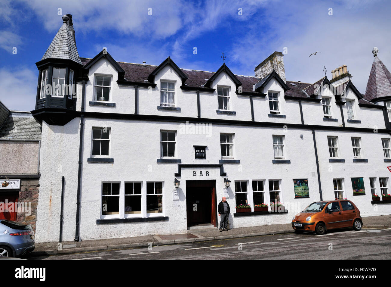 Uomo di fronte a un bar sulla Shore Street nella città di traghetto di Ullapool, Highlands scozzesi Foto Stock