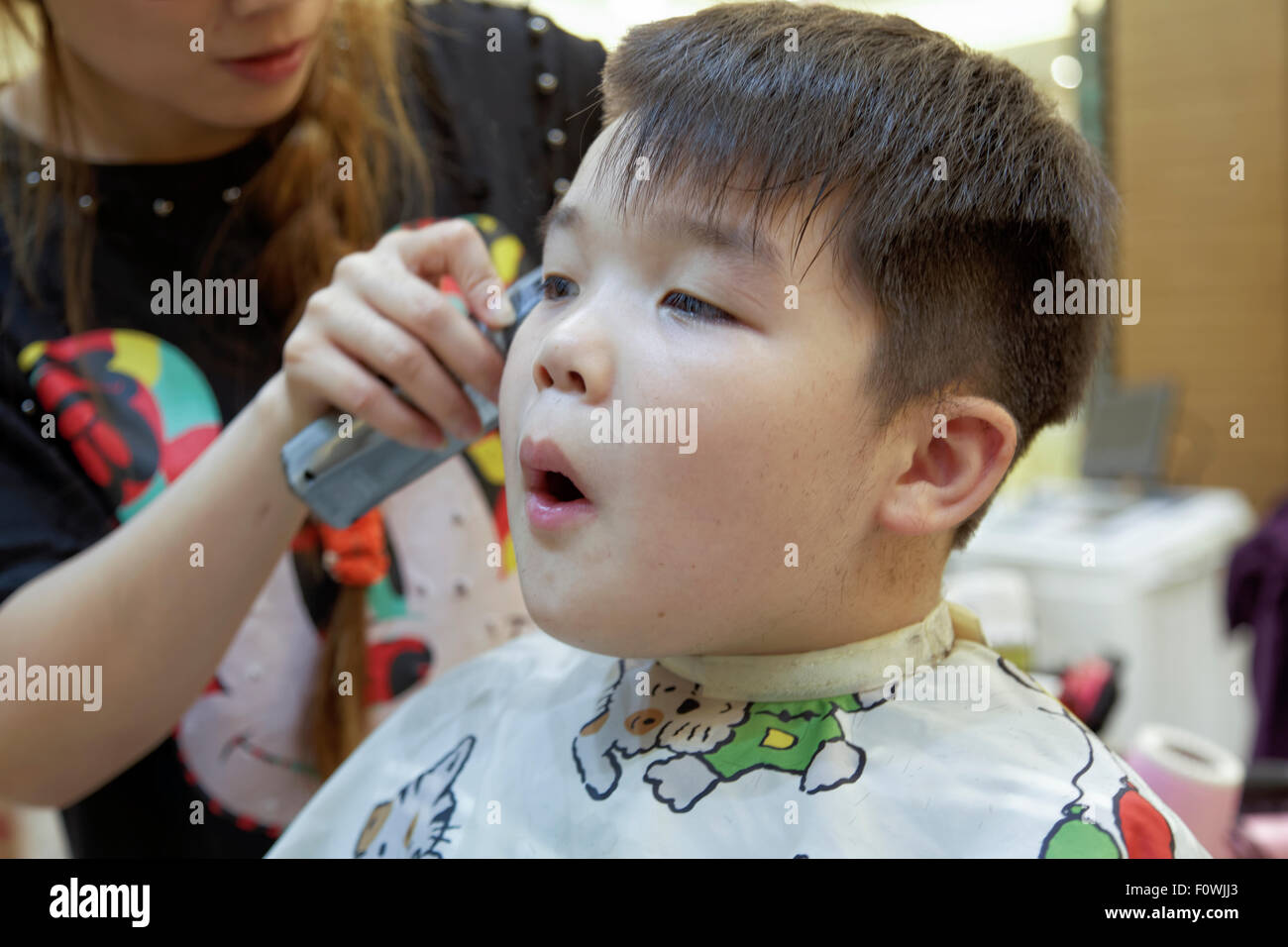 A 7 anno di età razza mista ragazzo di ottenere un taglio di capelli Foto Stock