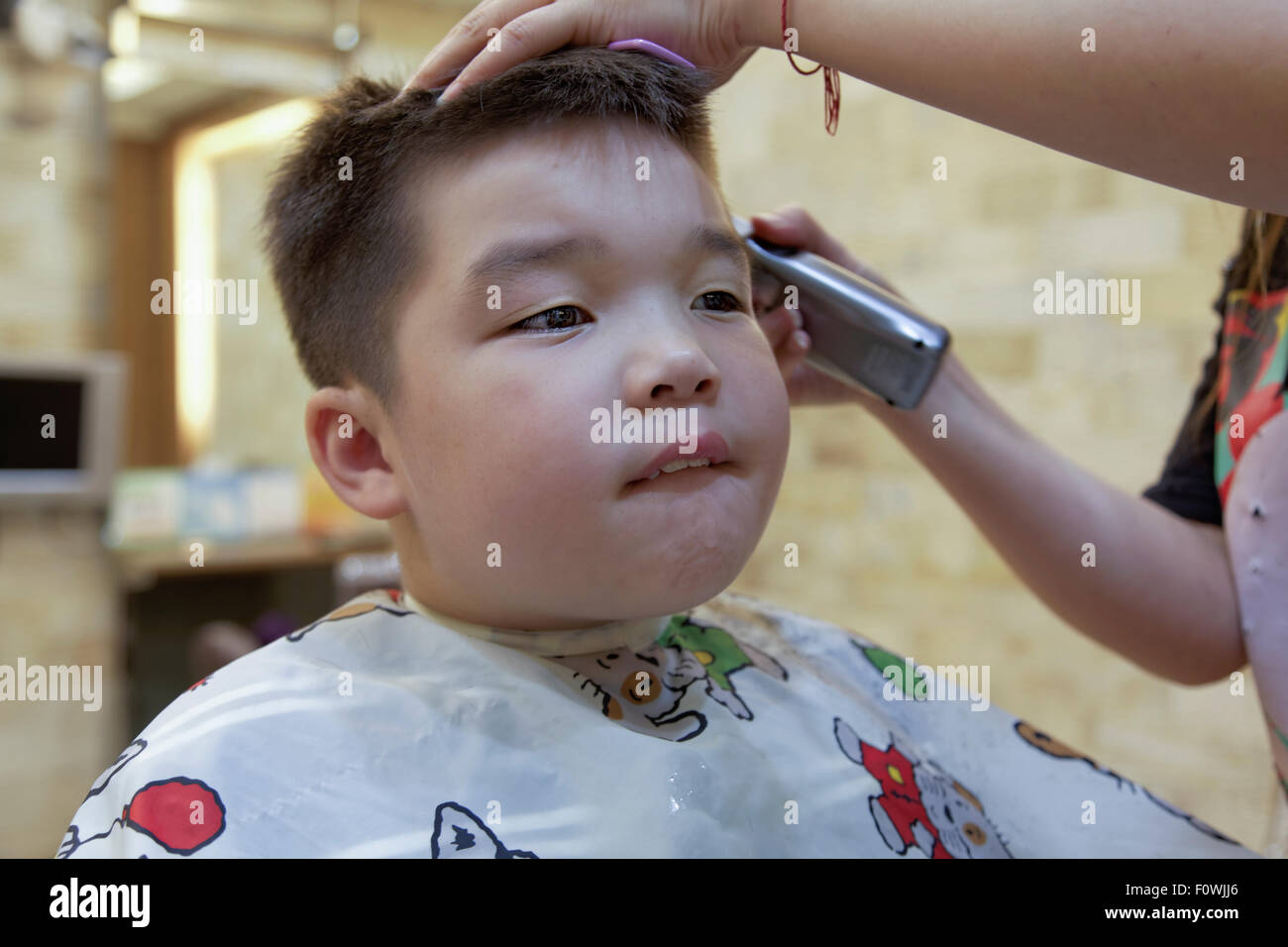 A 7 anno di età razza mista ragazzo di ottenere un taglio di capelli Foto Stock