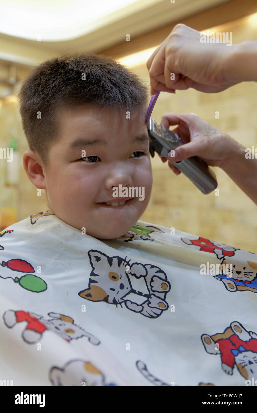 A 7 anno di età razza mista ragazzo di ottenere un taglio di capelli Foto Stock