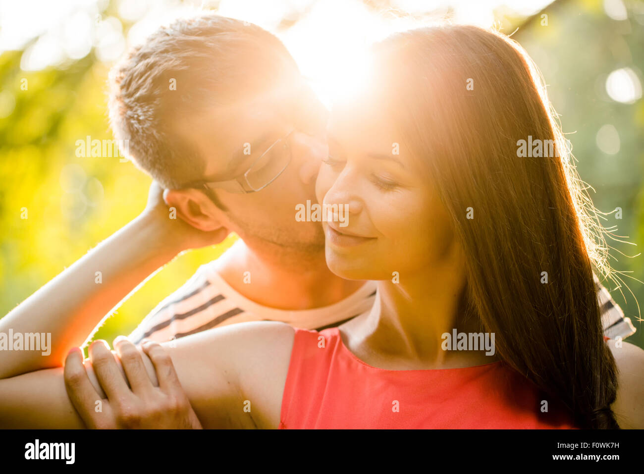 Romantico coppia giovane abbracciando e baciando al tramonto in natura Foto Stock