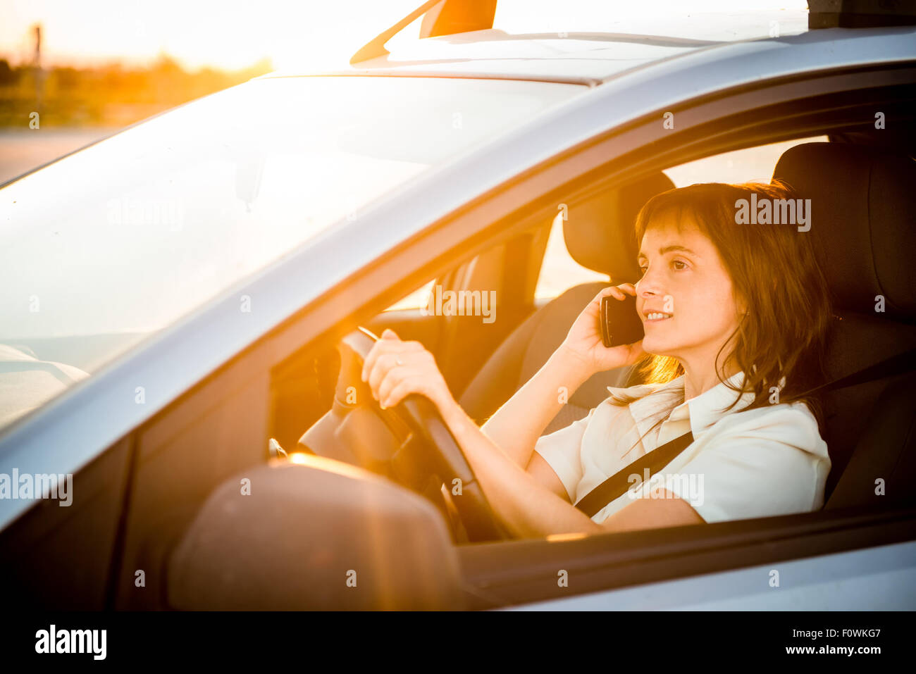 Azienda giovane donna alla guida di auto e telefono chiamante Foto Stock