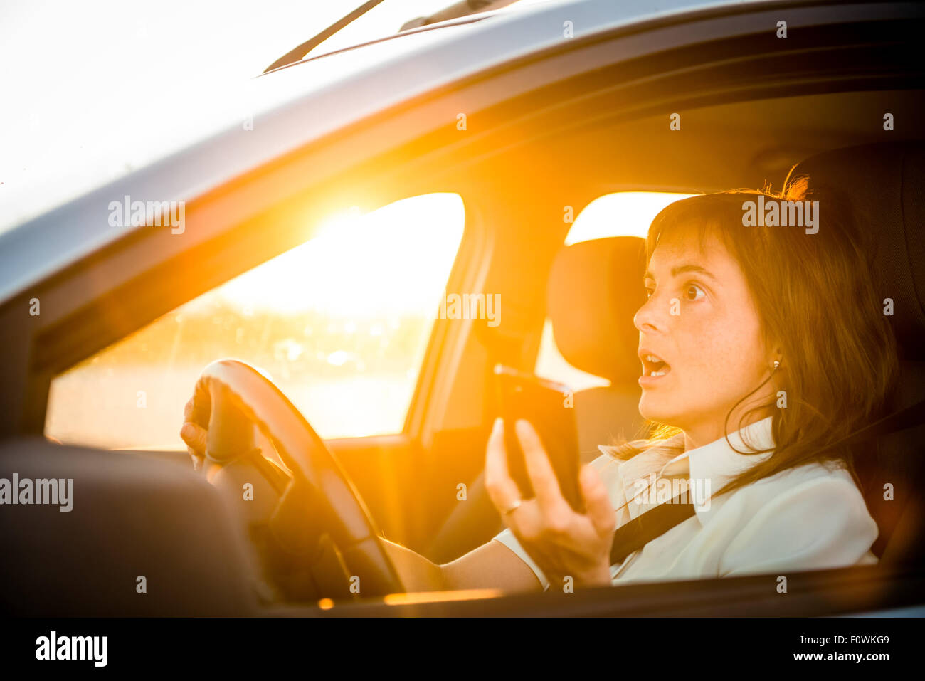 Young business woman drives auto con un cellulare in mano - azzardate Foto Stock