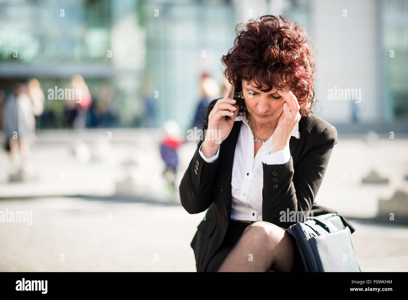 Senior business donna con mal di testa telefono chiamante outdoor in strada Foto Stock