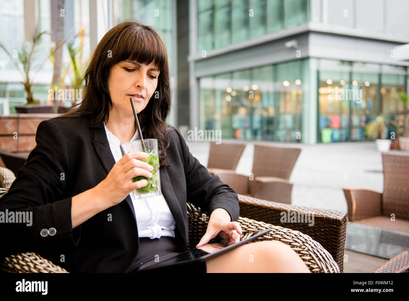 Senior business donna bere mojito outdoor in street bar e lavorando su tablet Foto Stock