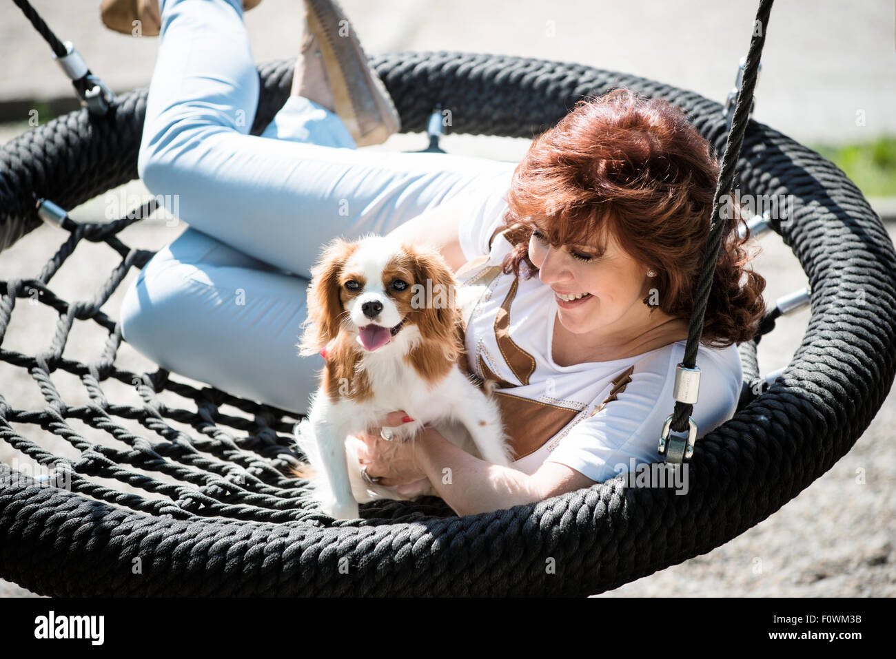 Donna matura oscillante con il suo animale amico al di fuori nel parco giochi Foto Stock