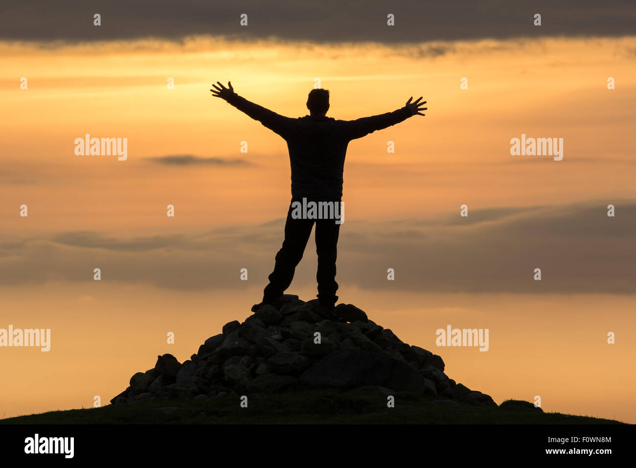 Alta grande, silhouette di un uomo sulla cima di una montagna Foto Stock