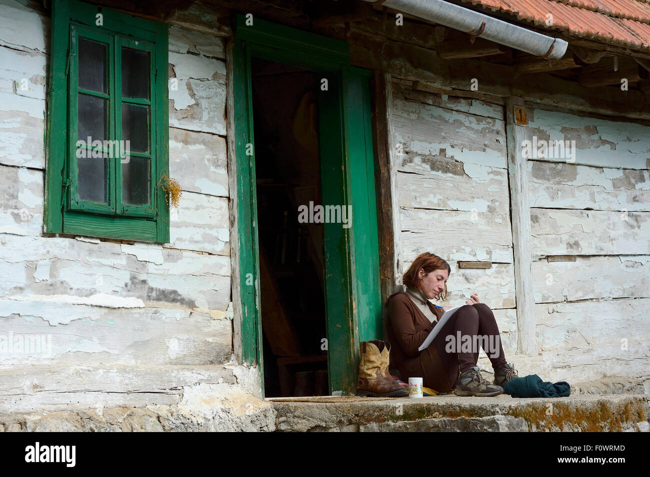 Donna sat iscritto al di fuori di Tiglio Retreat & Ranch, Velika Plana, Velebit mountains nature park, Croazia, aprile 2014. Foto Stock