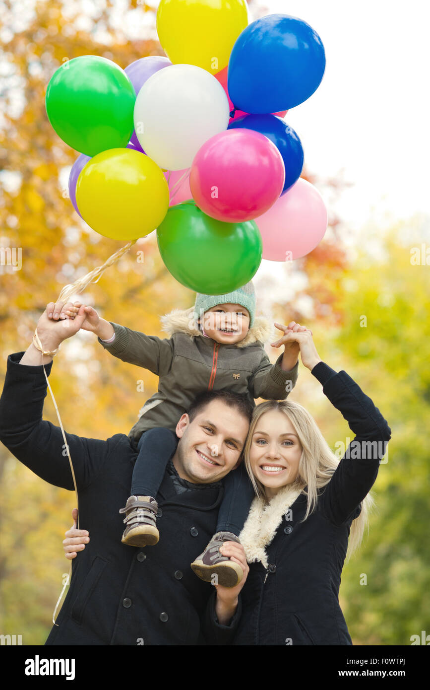 Felice famiglia con bambino e aria-palloncini, gita in autunno park Foto Stock
