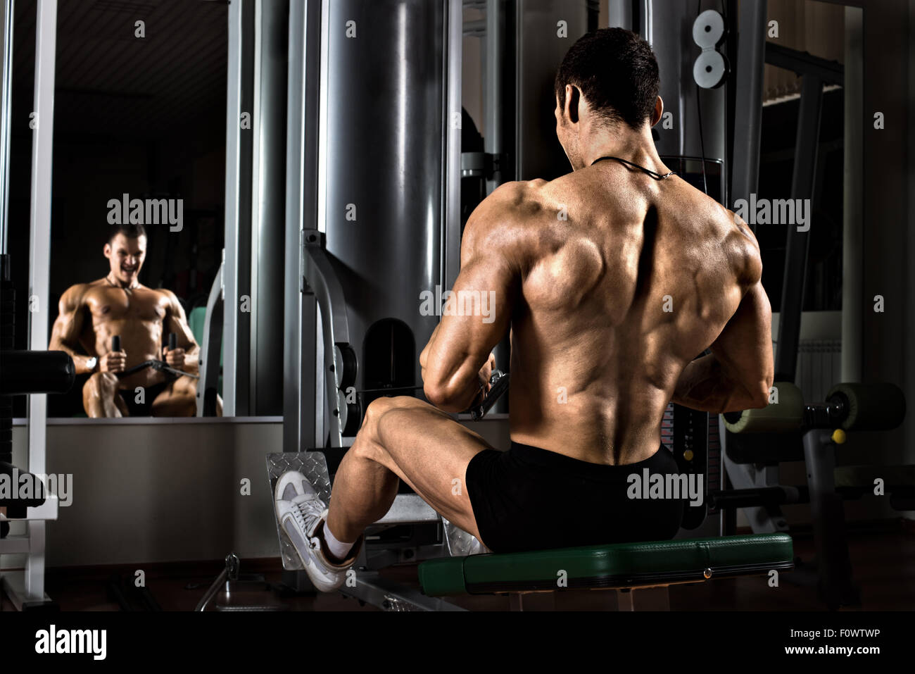Molto potere ragazzo atletico culturista, esecuzione di esercizio con palestra apparecchiatura sul muscolo più ampia della parte posteriore Foto Stock