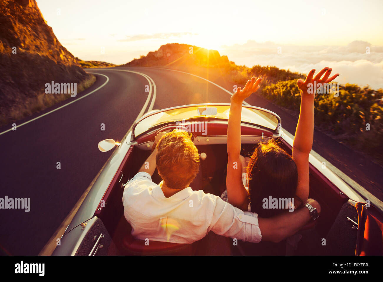 Coppia felice guida su strada di campagna nel tramonto in Classic Vintage auto sportive Foto Stock