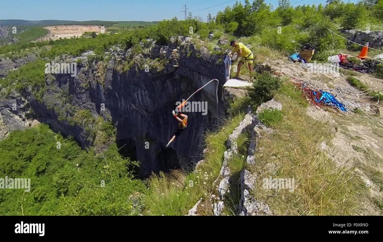 Bungee jumpers si precipitano sulla Prohodna entrata della caverna e turisti osservare la "gli occhi di Dio" fenomeno di pietra nei pressi del villaggio di Karlukovo, a est della capitale bulgara Sofia, Domenica, Giugno, 21, 2015. Prohodna è più notevole per i due di uguali fori calibrati nel soffitto della sua camera media che è stata formata attraverso erosione. I due grandi fori allungati nel suo soffitto che consentono la luce in grotta, sembrare solo un paio di occhi umani - da qui il nome "gli occhi di Dio". Prohodna è la più conosciuta attrazione nella Karlukovo Gorge, parte del parco geologico Iskar-Panega, su Foto Stock