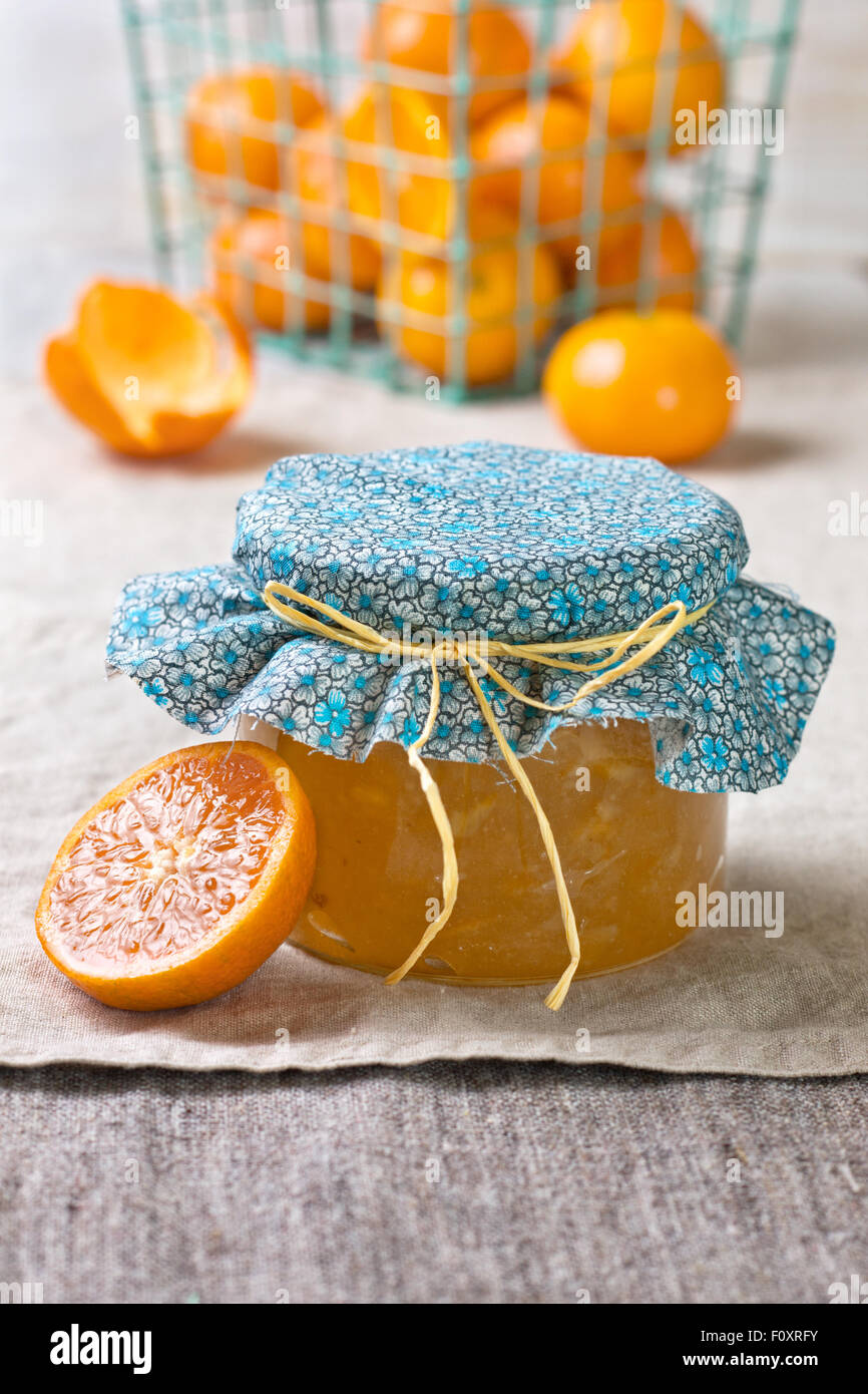 Tangerine inceppamento in un vasetto di vetro, tangerini su un sfondo di lino Foto Stock