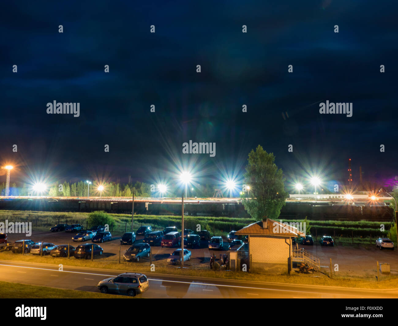 Parcheggio auto durante la notte con le luci di strada e incredibili nuvole scure Foto Stock