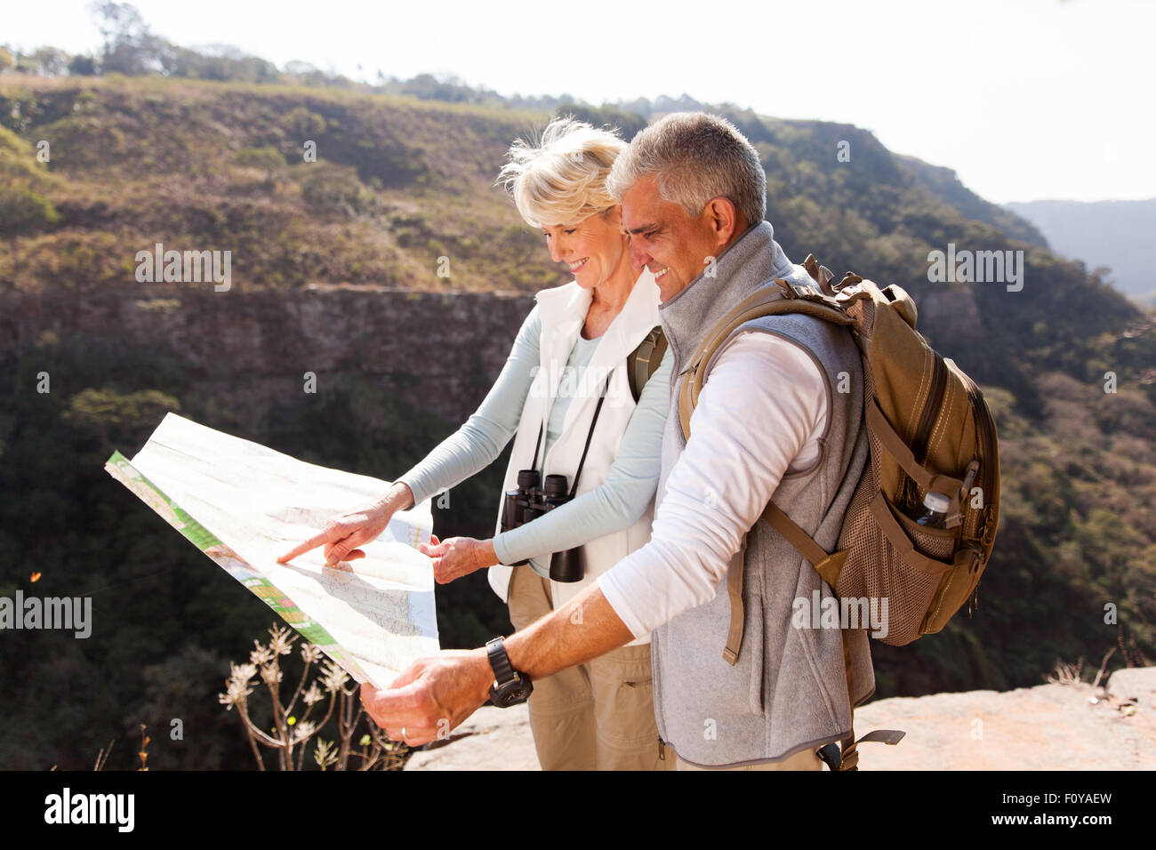 Attivo centro di età compresa tra gli escursionisti alla ricerca di una mappa sulla cima della montagna Foto Stock