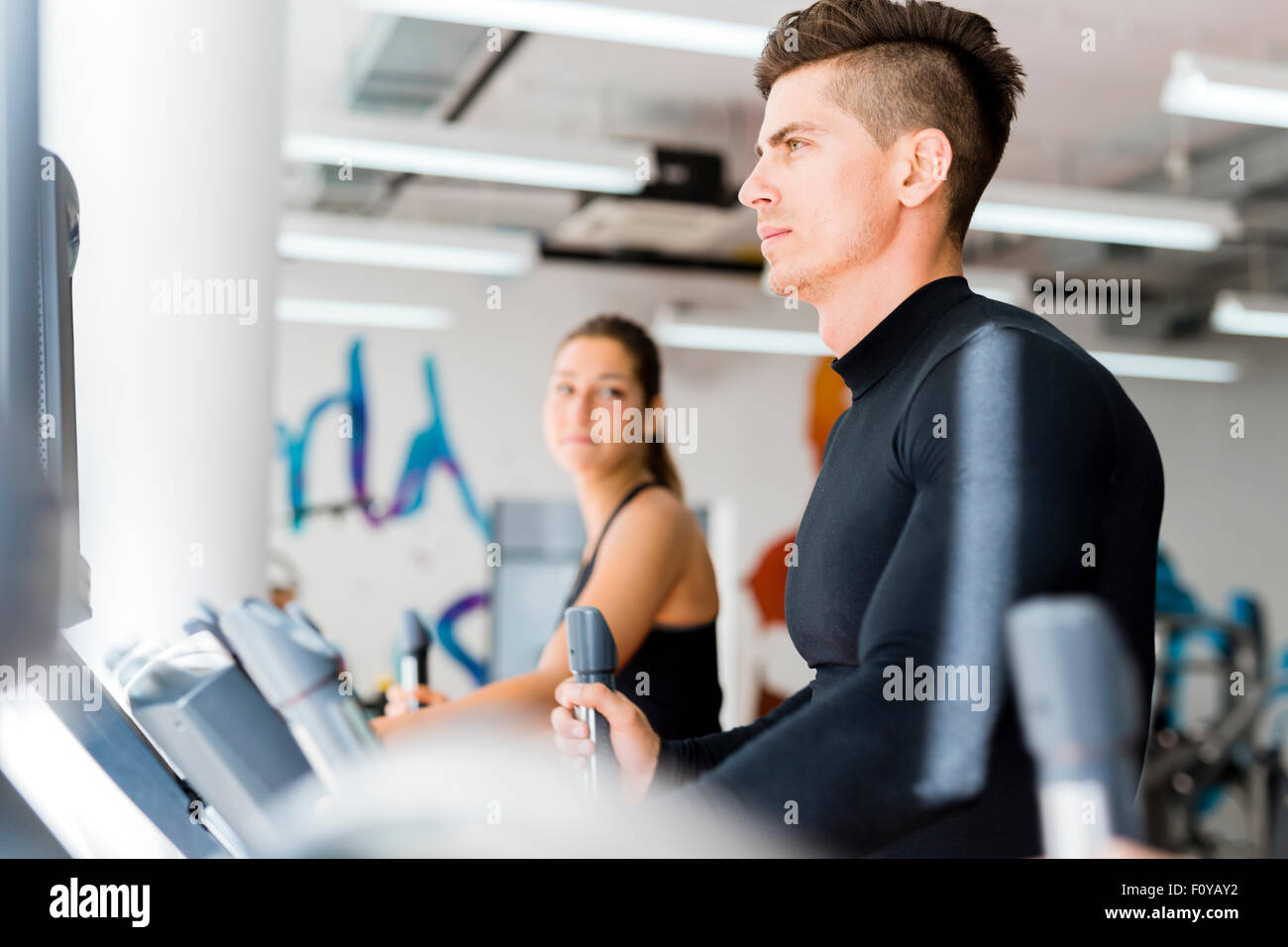 Giovani e sani, un gruppo di persone che lavorano su un trainer ellittico in un centro fitness Foto Stock