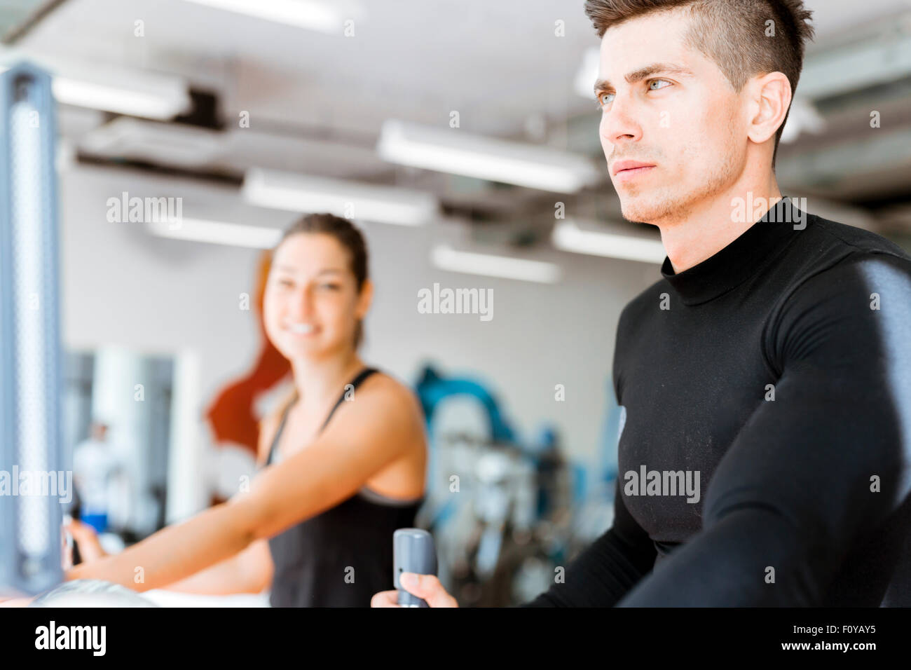 Giovani e sani, un gruppo di persone che lavorano su un trainer ellittico in un centro fitness Foto Stock