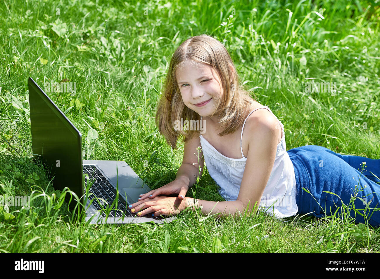 Ragazza utilizzando laptop sull'erba outdoor Foto Stock